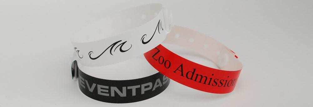 Custom plastic wristbands in white, red and black, stacked on one another